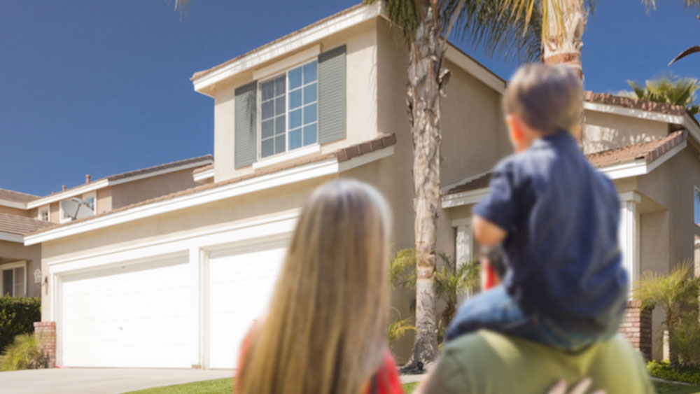 Young couple standing in front of their new home